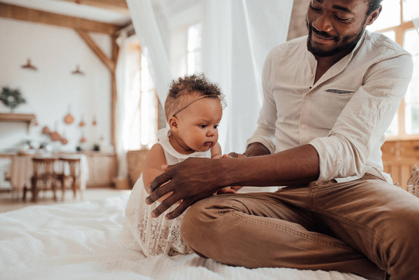 Połączenie ojca z dzieckiem. szczęśliwy czarny człowiek więzi z słodkie dziecko w domu - Zdjęcie, obraz