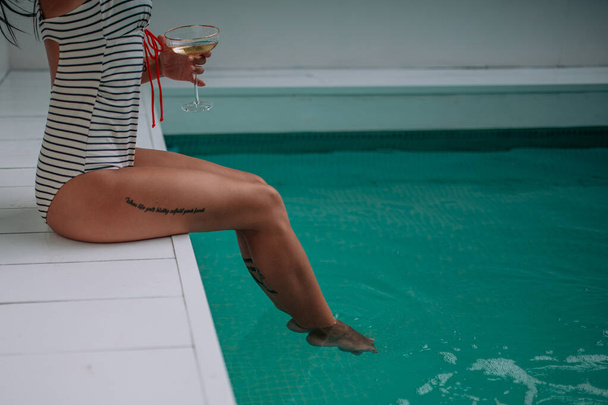 vista parziale di giovane donna con cocktail piscina nelle vicinanze - Foto, immagini