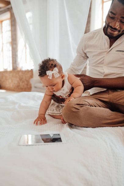 Связь с отцом. Счастливый чернокожий мужчина общается с милым младенцем дома - Фото, изображение