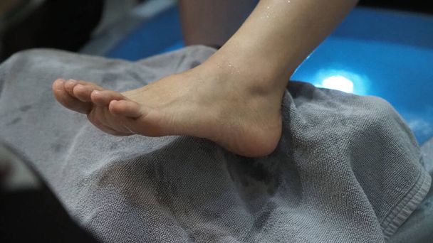 Foot Spa. Ženy bosé nohy masírují v automatu na mýdlovou vodu v lázeňství. Nohy žen vstupujících do koupele v horké vodě handheld - Fotografie, Obrázek
