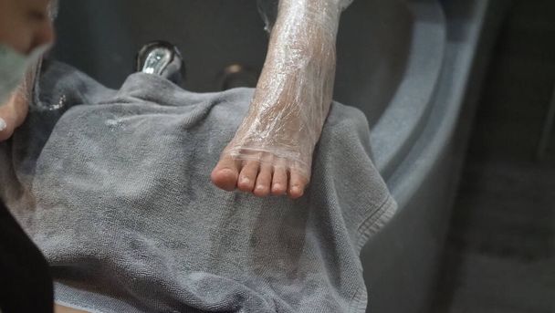 Ayak Spa 'sı. Kaplıcadaki sabun su makinesinde çıplak ayakla masaj yapan bir kadın. Kadınların ayakları sıcak su elde banyoya giriyor. - Fotoğraf, Görsel