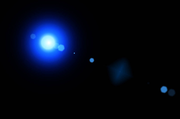 Ilustración de luz azul brillante con líneas de destello de lente y bokeh sobre fondo negro. Explosión de sol con destello de lente digital sobre fondo negro. Destello de estrella con rayos. - Foto, Imagen
