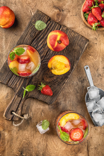 Summer lemonade top view. Cold drink with peach, strawberry, ice, mint leaves - Foto, immagini