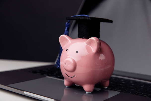 College, graduate, diploma concept. Pink piggy bank in cap on keyboard. Online education - Фото, изображение