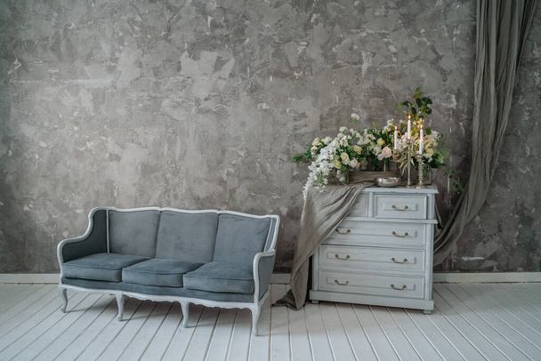 Grey sofa with chest of drawers against a gray wall. - Photo, Image