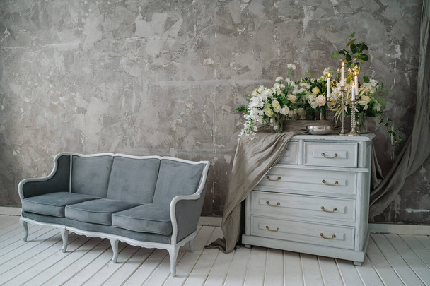 Graues Sofa mit Kommode vor grauer Wand. - Foto, Bild