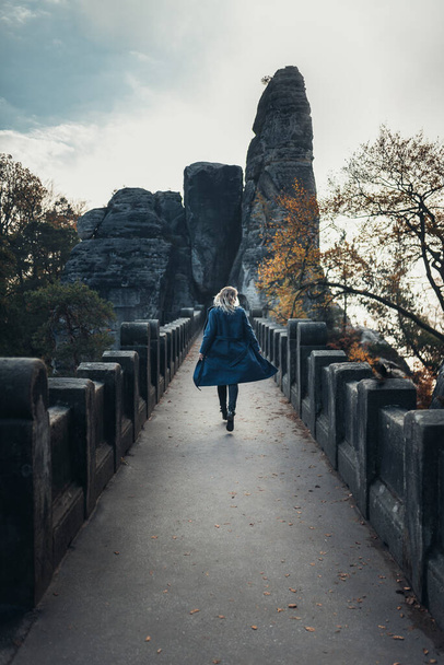 Una donna con un cappotto attraversa il ponte Bastei - Foto, immagini