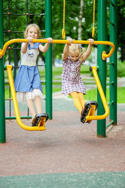 Duas meninas balançando no playground
 - Foto, Imagem