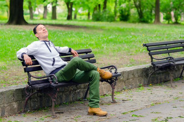 jonge man dagdromen op de Bank in het park - Foto, afbeelding