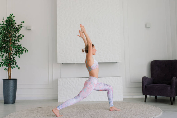 Gezondheidsconcept. Jonge mooie vrouw doet yoga oefening in een moderne kamer - Foto, afbeelding