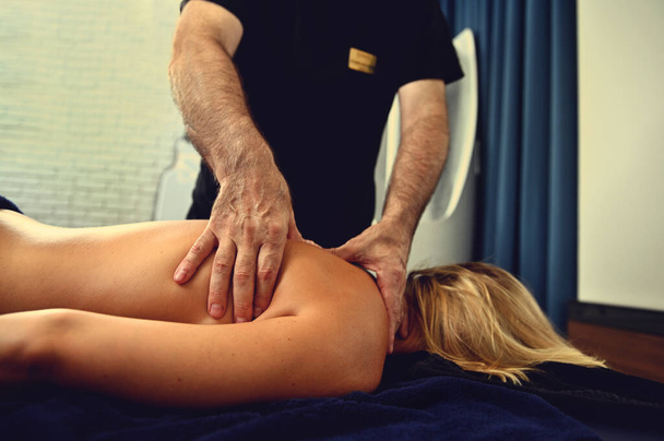 Profesionální masér pracující s klientem wellness centra. Nápravná a terapeutická profesionální masáž zad - Fotografie, Obrázek