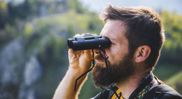 handsome man trekking in nature using binoculars slow travel - Photo, Image