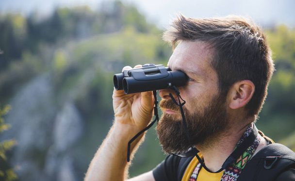 handsome man trekking in nature using binoculars slow travel - Photo, Image