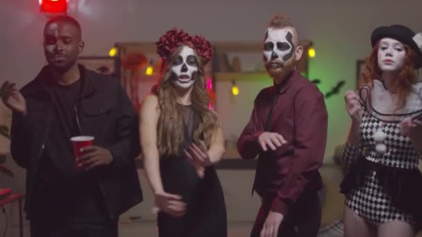 Slowmo záběr šťastných mladých mužů a žen v halloween kostýmy tančí společně na večírku a dívá se na kameru - Záběry, video