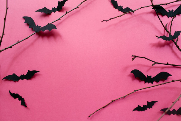 Halloween decorations with bats and branches on pink background. Halloween concept. Flat lay, top view, copy space - 写真・画像