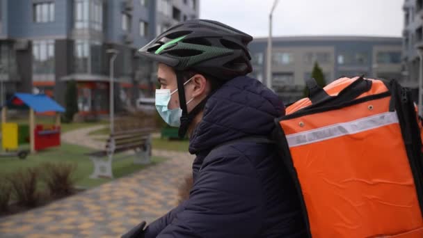 Maskeli yemek kuryesi şehirde bisiklet sürüyor. - Video, Çekim