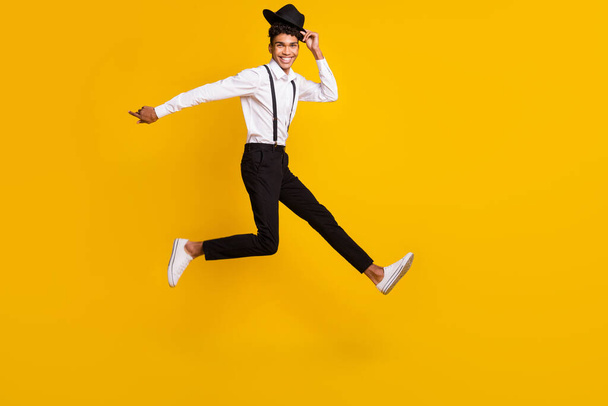 Full length photo portrait of african american man running taking off hat jumping up isolated on vivid yellow colored background - Photo, Image