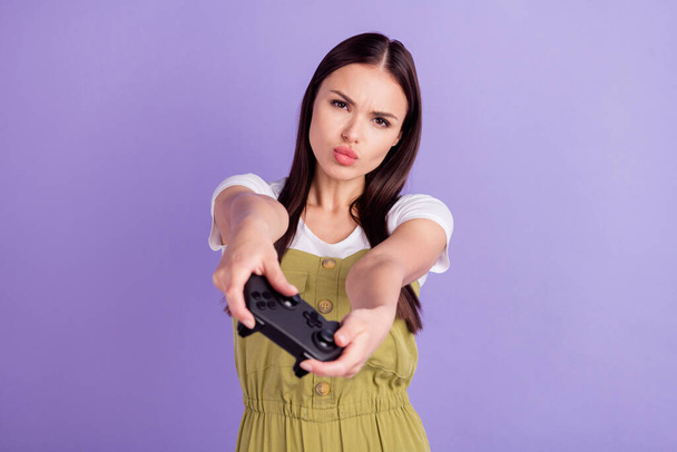 Photo of cute upset young woman dressed khaki overall playstation loser isolated violet color background - Фото, зображення