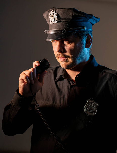 un policier parle sur un talkie-walkie alors qu'il patrouille dans un portrait rapproché - Photo, image