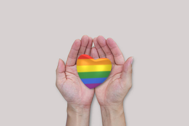Cuore arcobaleno LGBTQ in mano su sfondo bianco. Diversa uguaglianza libertà d'amore. - Foto, immagini