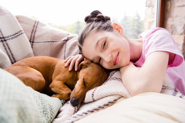 Portrait of attractive dreamy cheery preteen girl resting with cute doggy puppy spending time staying alone at light home house indoors - Fotografie, Obrázek