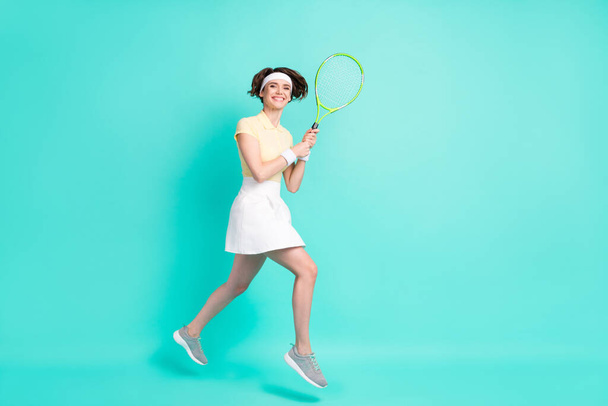 Full size photo of happy cheerful good mood girl jumping playing tennis exercising isolated on turquoise color background - Photo, Image