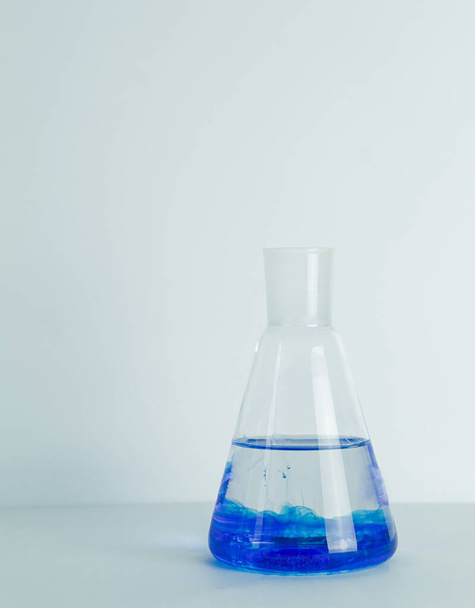 Frasco cónico Erlenmeyer de vidrio de laboratorio lleno de líquido químico azul para un experimento químico en un laboratorio de investigación científica. Foto de alta calidad - Foto, Imagen
