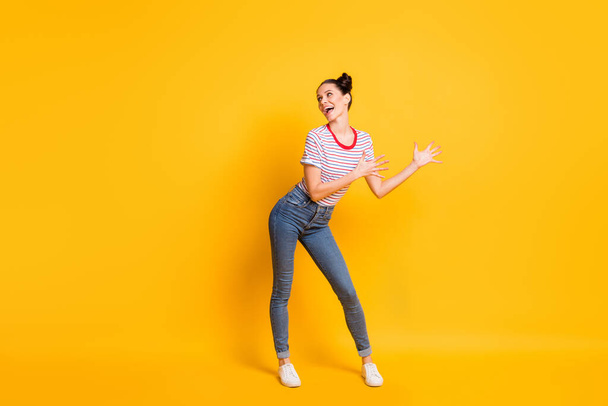 Photo of funny charming young lady wear striped t-shirt dancing looking empty space isolated yellow color background - Photo, Image