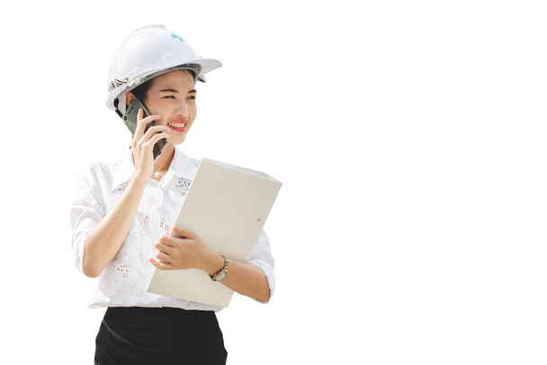 Aziatische engineering vrouwen toezichthouders dragen hardhat holding document bestanden praten mobiele telefoon geïsoleerd op witte achtergrond - Foto, afbeelding