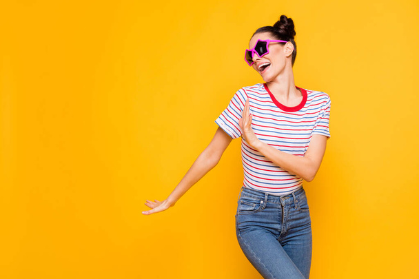 Photo of sweet cute young lady wear striped t-shirt dark eyewear dancing empty space isolated yellow color background - Foto, afbeelding