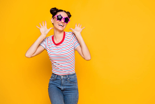 Photo of cute charming woman wear striped t-shirt dark glassed dancing rising arms empty space isolated yellow color background - 写真・画像
