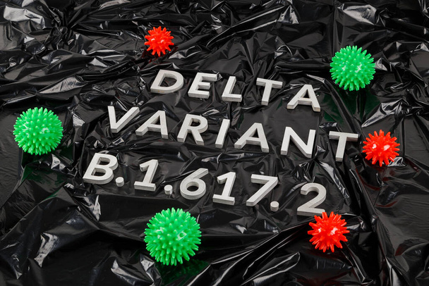 palabras variante delta B.1.617 colocada con letras de metal plateado sobre fondo de bolsa de plástico negro arrugado en perspectiva diagonal - Foto, Imagen