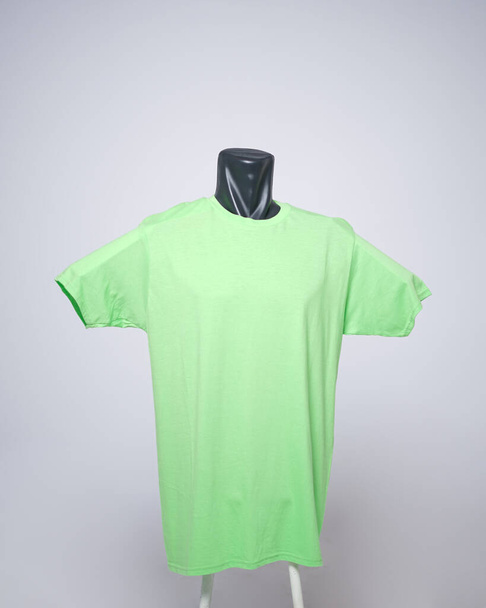 T-Shirt-Vorlage für Männer in neon- oder grüner Farbe, Vorderansicht, natürliche Form auf unsichtbarer schwarzer Schaufensterpuppe, damit Ihr Modell gedruckt werden kann, isoliert auf schlichtem weißem Hintergrund. Freier Platz für Ihre Anzeige. - Foto, Bild