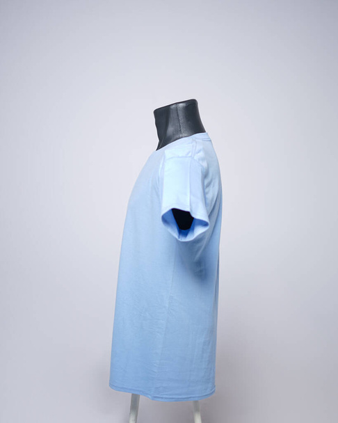 Hellblaue T-Shirt-Vorlage für Männer, Seitenansicht, natürliche Form auf unsichtbarer schwarzer Schaufensterpuppe, für den Druck Ihrer Attrappe, isoliert auf schlichtem weißem Hintergrund. Freier Platz für Ihre Anzeige. - Foto, Bild