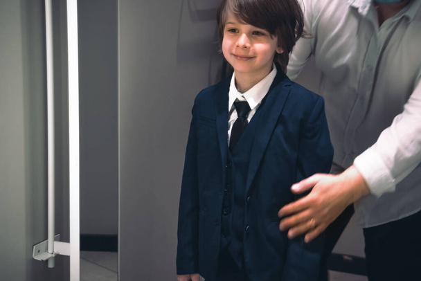 Sorrindo menino e seu pai tentando uniforme escolar para o futuro aluno.  - Foto, Imagem