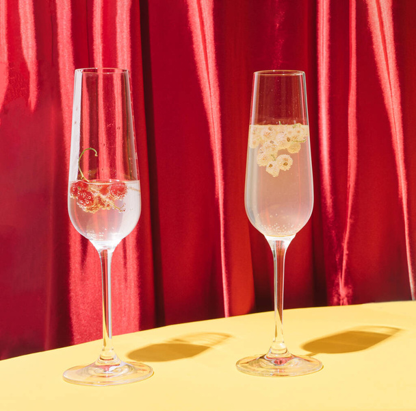 Twee cocktails met rode en witte bessen. Stijlvol fluweel zijde rode textuur achtergrond en warm gele bodem. - Foto, afbeelding