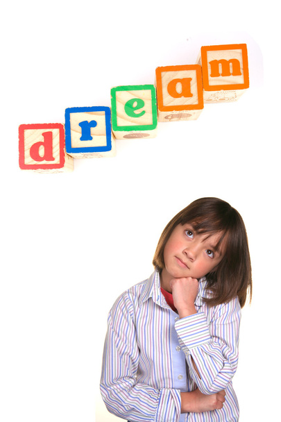 A young girl in a dreaming posture with the word dream above in blocks. - Photo, Image