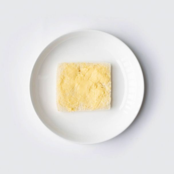 Butter on a slice of bread isolated on white background on a plate. Cooking breakfast. Wholewheat. Healthy food. Dairy product. - Zdjęcie, obraz