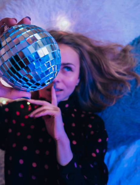 Beautiful young woman lying down with disco ball. Party concept. New year christmas or birthday party. Joyfull happines and magic dreaming - Fotoğraf, Görsel