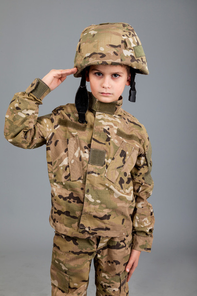 Saluting soldier. Young boy dressed like a soldier - Фото, изображение