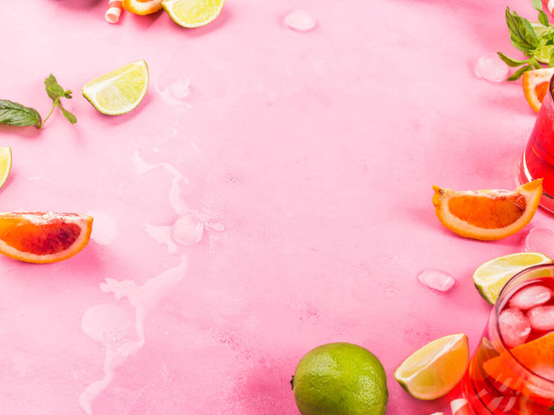 Summer pink background with citrus slices, ice and mint leaves. Ingredients for fresh drink cocktail - Photo, Image