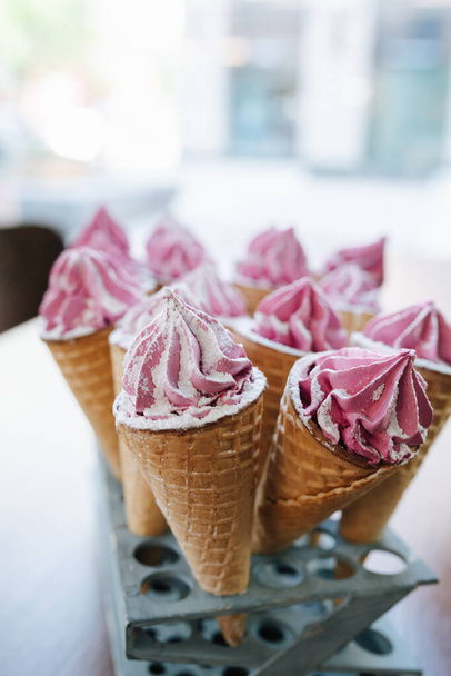 Sweet waffle cones with pink cream on a special stand. Blurred background. - Fotografie, Obrázek