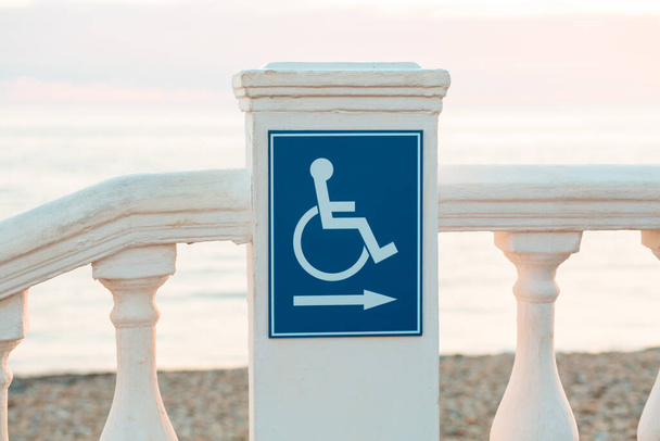 Міжнародний день інвалідності. Блакитний знак з калікою на пляжі. Концепція догляду за інвалідами. - Фото, зображення