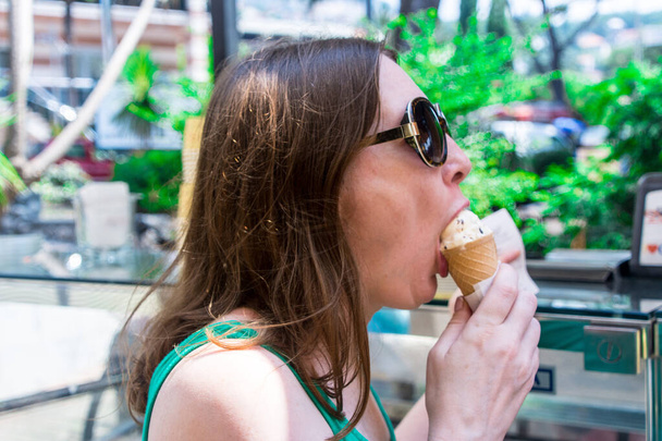 Όμορφη γυναίκα με γυαλιά ηλίου τρώει παγωτό χωνάκι - Φωτογραφία, εικόνα