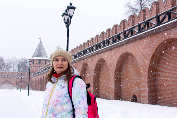 Russland, Tula. 9. Januar 2021. Rote Backsteinmauern und Türme des Kremls von Tula im Winter. Touristin in den Mauern der Festung. - Foto, Bild