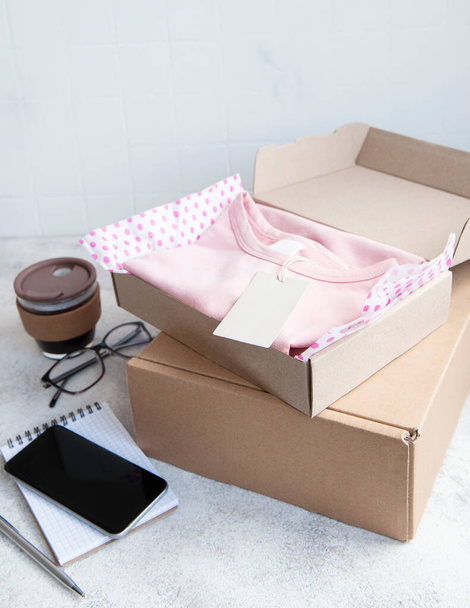 Clothes for kids in an open cardboard box. Online shopping concept. Delivery of clothes. - Foto, Imagen