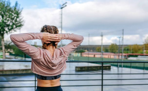 Unrecognizable young sportswoman stretching neck and shoulders outdoors - Фото, зображення