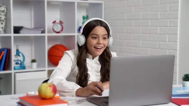 niño alegre en uniforme escolar y auriculares terminó la lección en línea en el ordenador portátil, webinar - Metraje, vídeo