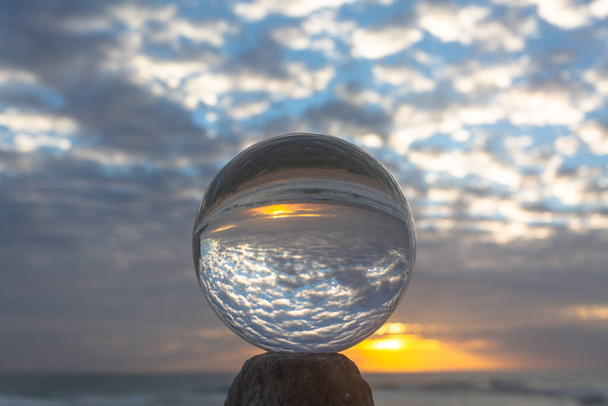 piękna chmura i złoty zachód słońca wewnątrz kryształowej kuli umieszczonej na drewnie przy plaży - Zdjęcie, obraz