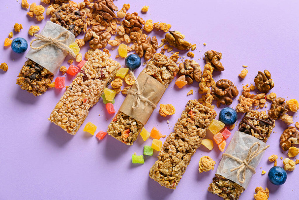 Barras de cereales saludables, arándanos y frutas confitadas sobre fondo de color - Foto, imagen